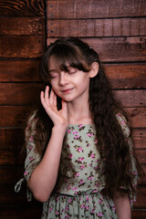 Cute portrait of a girl on a wooden background. Emotional child in a dress.