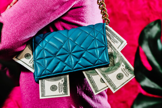 carries a blue purse full of fake dollar bills