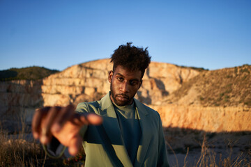 Stylish black man pointing to camera in nature