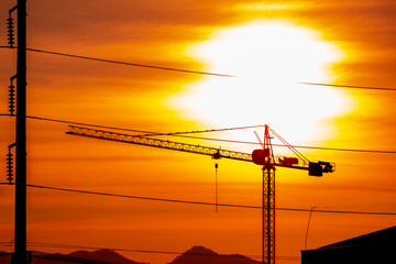 Silhouette building construction crane near the high voltage cable during sunset. construction site...