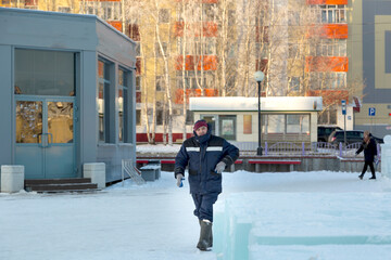 A worker in a blue winter suit walks through a construction site