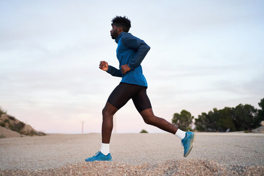 Black runner jogging in hilly terrain