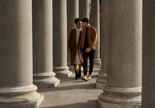 Couple running while holding hands between columns