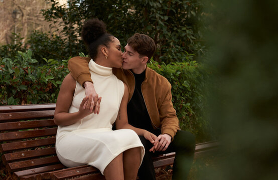 Portrait of a multiracial couple kissing at a bench