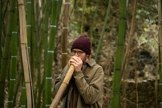 Portrait of young man playing bamboo didgeridoo
