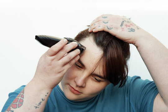 Non-binary person shaving his head