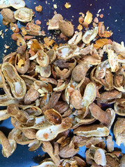 High angle close-up view of a pile of cracked peanut shells on a dark background