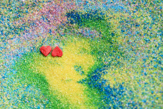 two hearts on a colorful background. decorative colored sand as a background © Tasha