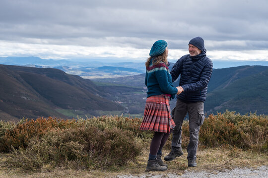 a couple holding hand on a mountaintop
