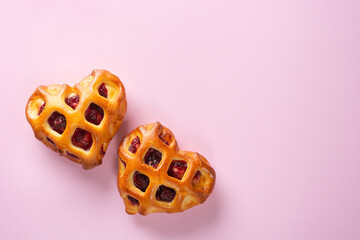 Valentine's day banner. Pair of heart-shaped buns with berry jam and a lattice crust on a rosy background. Copy space for text, flat lay