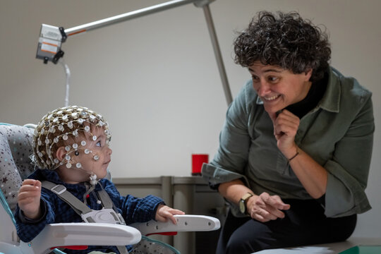 Researcher making neural study on kid in EEG cap
