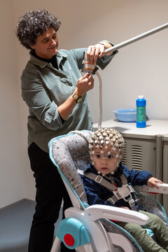Researcher making neural study on kid in EEG cap