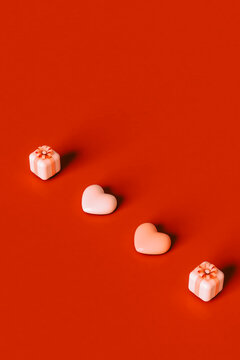  a row of 3D hearts and pink present on red background.
