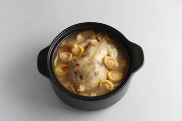 freshly hot stewed whole kampong chicken with abalone seafood in clay pot herbal soup on white background