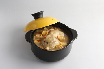 freshly hot stewed whole kampong chicken with abalone seafood in clay pot herbal soup on white background