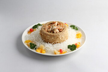 deep fried crispy yam ring with stir fried seafood meat vegetable and cashew nut in sauce and white vermicelli on white background chinese banquet menu