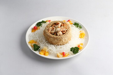 deep fried crispy yam ring with stir fried seafood meat vegetable and cashew nut in sauce and white vermicelli on white background chinese banquet menu