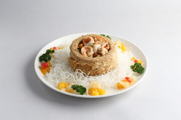 deep fried crispy yam ring with stir fried seafood meat vegetable and cashew nut in sauce and white vermicelli on white background chinese banquet menu