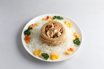 deep fried crispy yam ring with stir fried seafood meat vegetable and cashew nut in sauce and white vermicelli on white background chinese banquet menu