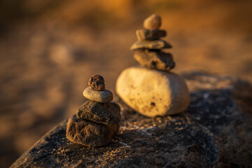 A cairn on a beach with cliffs and water in the blurry background