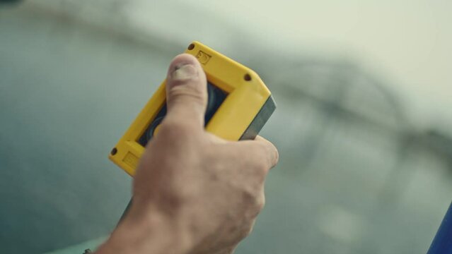 Machine control button.Worker with broken nails holding plastic yellow stop button. Stopping the industrial process. E-stop button in production.