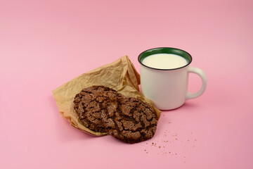 Mug of fresh milk and chocolate cookies on color pink background