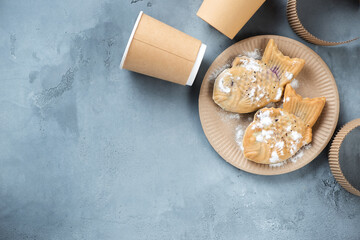Japanese taiyaki cakes with sweet filling on a beige carton takeaway plate, top view on a grey concrete background, horizontal shot with copyspace