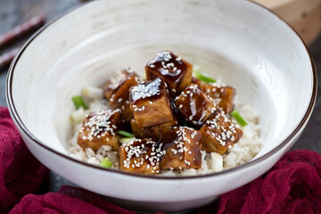 Beige bowl with teriyaki tofu and white rice, selective focus, close-up, horizontal shot