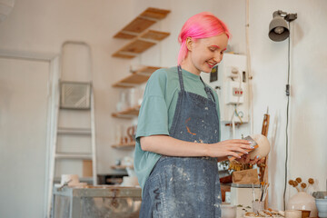 Potter woman working with ceramic dishes in workshop