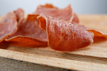 Meat chips lie on a wooden surface.