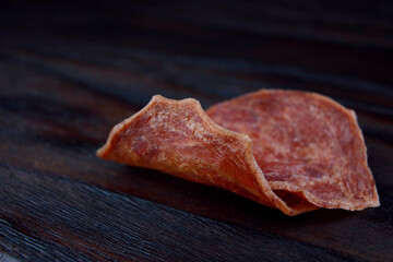 Two pieces of meat chips lie on a beautiful wooden surface.
