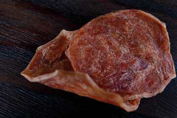 Two pieces of meat chips lie on a beautiful wooden surface.