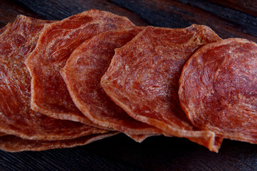 Meat chips are lined up on a wooden surface.