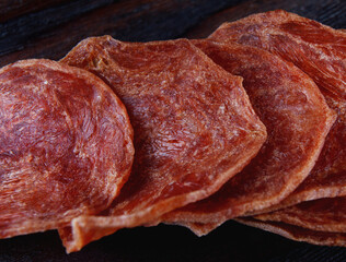 Meat chips are lined up on a wooden surface.