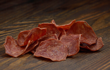 Meat chips on a wooden board. Beautiful placer of thin slices of dried meat.
