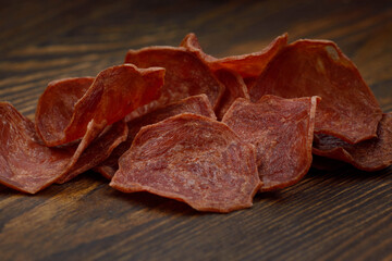 Meat chips on a wooden board. Beautiful placer of thin slices of dried meat.