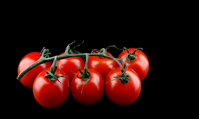 Branch of beautiful tomato isolated on black background.