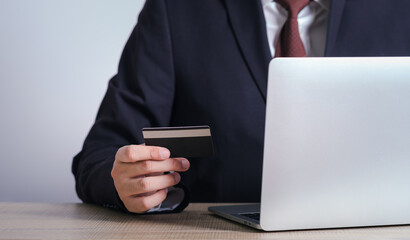 businessman is using a credit card with a laptop for financial transactions. Online banking purchase product on internet in home office or online shopping. Convenience in the world of technology.