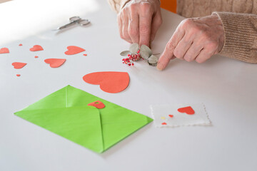 DIY valentine's day card. Senior woman hands are closing an envelope