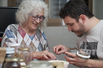 Mother and adult son preparing something in the kitchen together.