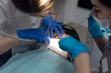 The orthodontist puts metal braces on a girl.