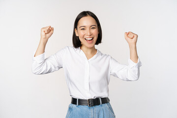 Enthusiastic asian woman rejoicing, say yes, looking happy and celebrating victory, champion dance,...