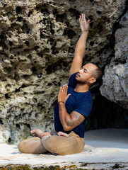 Attractive Asian man sitting in Lotus pose. Padmasana. Side extension. Closed eyes. Side tilt. Yoga retreat. Healthy lifestyle. Zen life. Flexible spine. Thomas beach, Bali