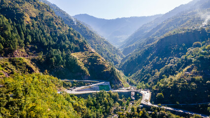An Areal view of a zigzag Road between two mountains in the green.