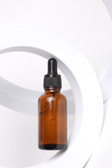 Amber glass dropper bottle on round form on white background. Cosmetic container mock-ups....