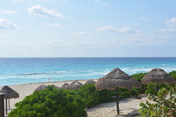 azure sea and sandy beach with umbrellas and bench in Cancun