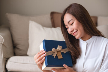 Portrait image of a young woman receiving and holding a present box at home