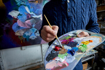 Adult man painter painting on canvas background