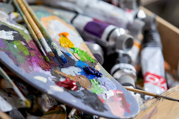 Tubes of oil paint, palette and artist paintbrushes closeup