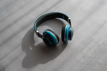 Turquoise and black headphones against a gray background. Wireless device for listening to music...